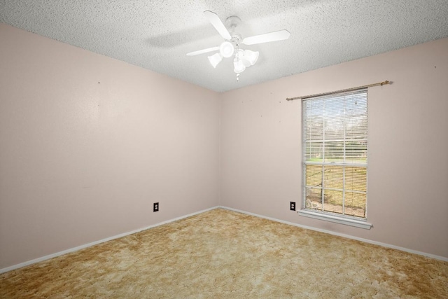 carpeted spare room with a textured ceiling, ceiling fan, and baseboards