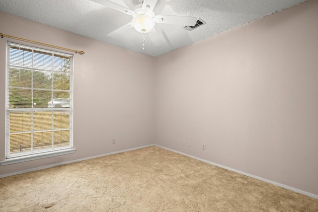 carpeted spare room with baseboards, ceiling fan, visible vents, and a textured ceiling