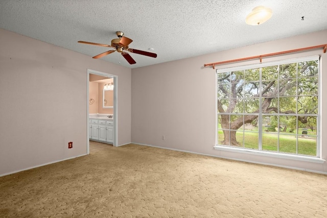 carpeted empty room featuring baseboards, ceiling fan, a textured ceiling, and a sink