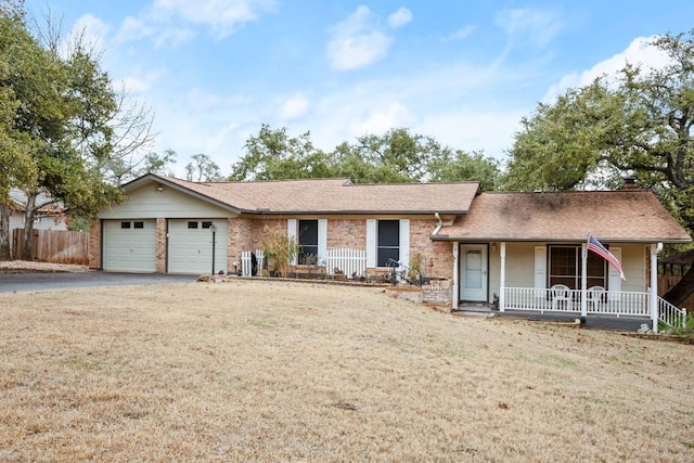 single story home featuring covered porch, a garage, brick siding, driveway, and a front yard