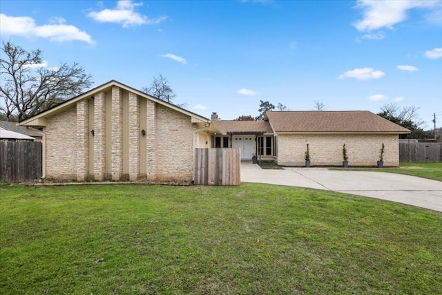 view of front facade with concrete driveway, a front yard, and fence