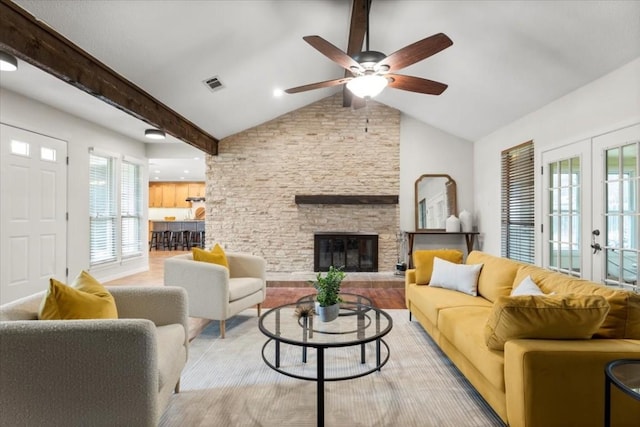 living room with french doors, vaulted ceiling with beams, a fireplace, visible vents, and a ceiling fan