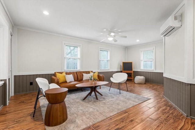 living room featuring plenty of natural light, wainscoting, ornamental molding, and a wall unit AC