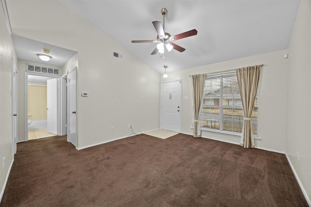 carpeted empty room with vaulted ceiling, baseboards, visible vents, and a ceiling fan