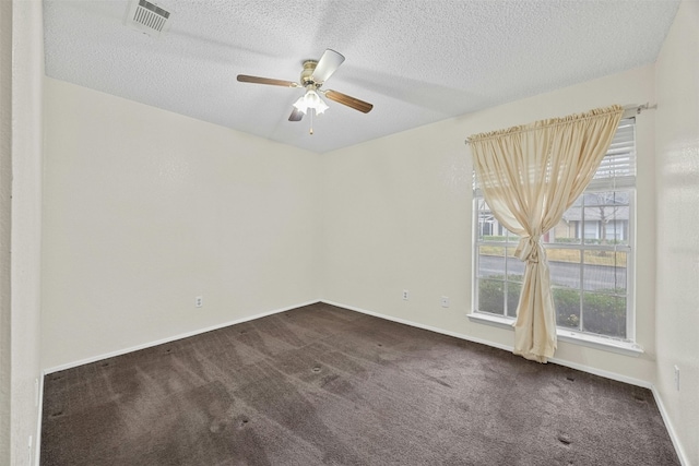 unfurnished room featuring visible vents, dark colored carpet, and a textured ceiling