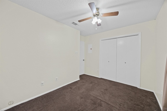 unfurnished bedroom featuring a closet, visible vents, dark carpet, ceiling fan, and a textured ceiling