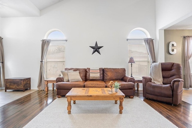 living room with wood finished floors, baseboards, and a towering ceiling