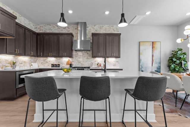 11 Doverland Dr, Lakeway, TX 78738 - kitchen with wall chimney range hood, a sink, dark brown cabinets, light countertops, and recessed lighting