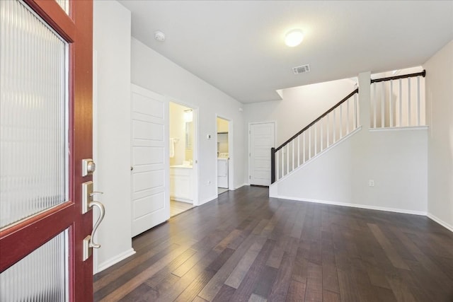 foyer entrance featuring dark wood-style flooring, stairway, visible vents, and baseboards