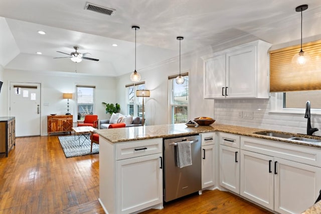 kitchen with visible vents, hanging light fixtures, open floor plan, white cabinets, and a sink