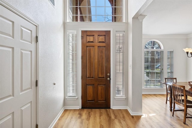 entryway featuring decorative columns, visible vents, light wood-style floors, ornamental molding, and baseboards