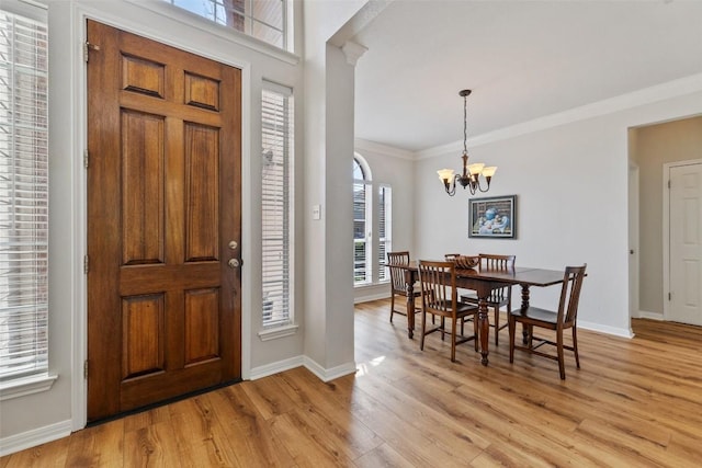 foyer entrance featuring baseboards, light wood-style floors, an inviting chandelier, and crown molding