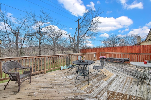 wooden terrace with outdoor dining area and fence