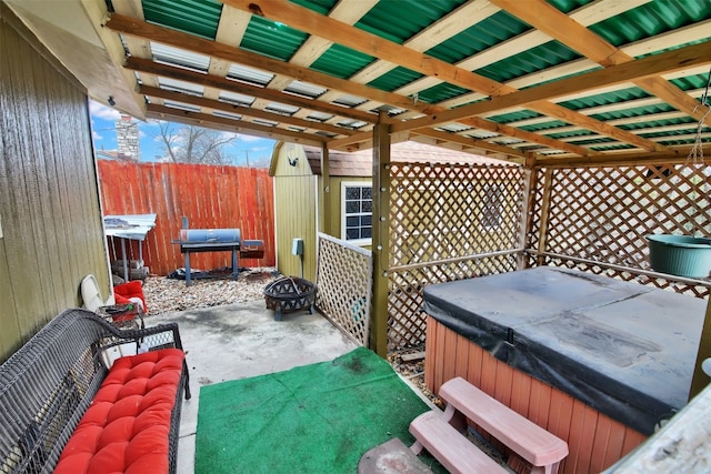 view of patio / terrace with a hot tub, fence, and a fire pit