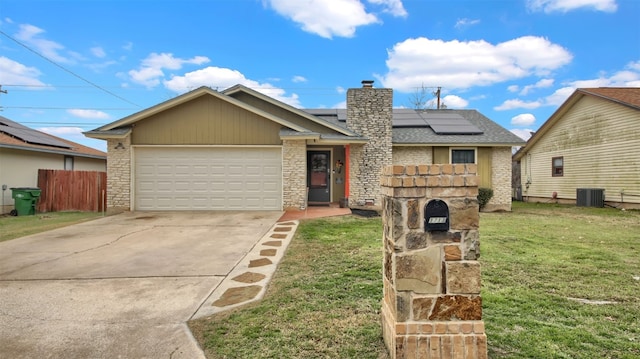 view of front of house featuring an attached garage, solar panels, driveway, a front lawn, and a chimney