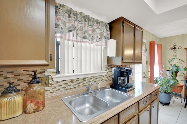 kitchen with light tile patterned floors, decorative backsplash, light countertops, and a sink