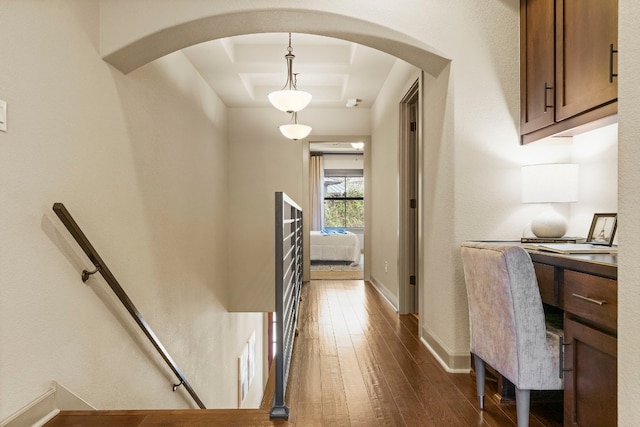 hallway with arched walkways, dark wood-style flooring, and baseboards