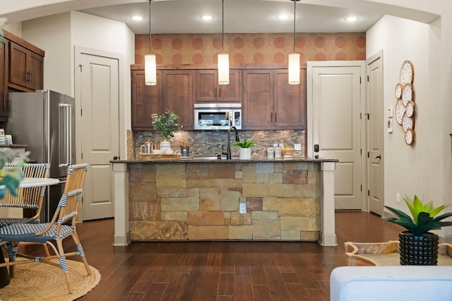 kitchen featuring decorative backsplash, stainless steel appliances, dark wood finished floors, and decorative light fixtures