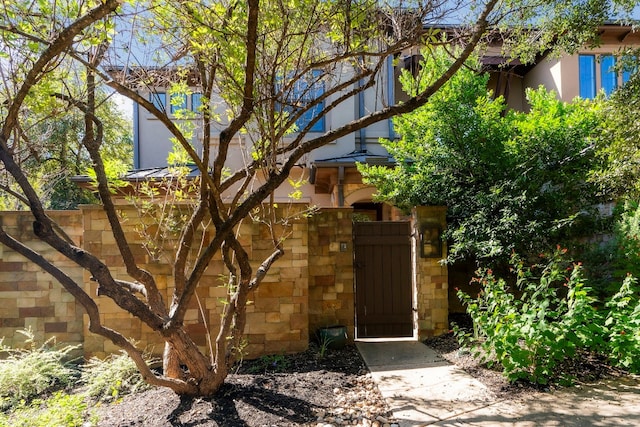 exterior space featuring stone siding and a gate