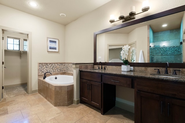 bathroom featuring double vanity, a stall shower, a garden tub, and a sink