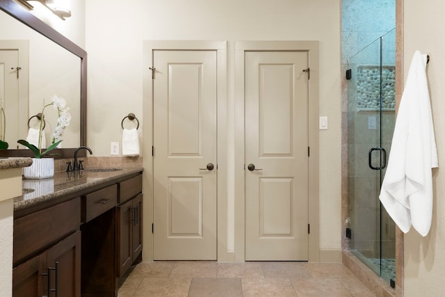 full bathroom featuring stone finish floor, a shower stall, and vanity