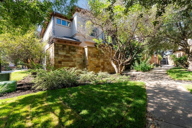 view of front of house featuring stone siding, a front lawn, and stucco siding