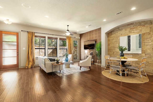 living area featuring visible vents, dark wood finished floors, a textured ceiling, and baseboards