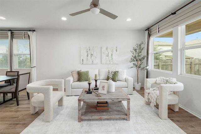 living room featuring baseboards, light wood finished floors, a ceiling fan, and recessed lighting