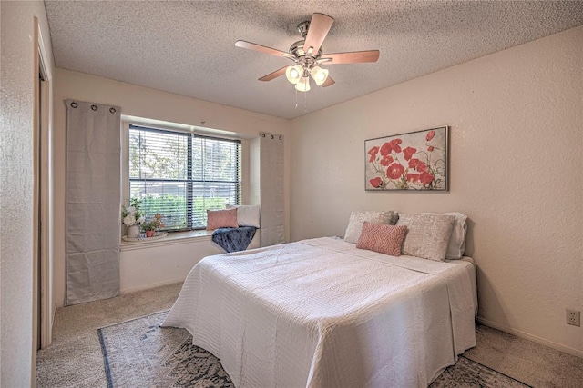 bedroom featuring a ceiling fan, light colored carpet, a textured wall, and a textured ceiling
