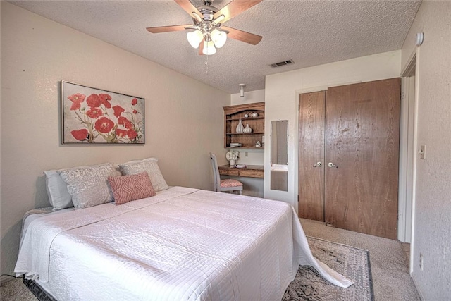 bedroom featuring a textured ceiling, carpet floors, visible vents, a ceiling fan, and a closet