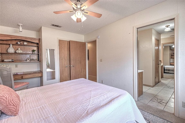 bedroom with a textured ceiling, ceiling fan, a textured wall, and visible vents