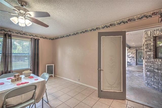dining room with light tile patterned floors, a ceiling fan, baseboards, and a textured ceiling