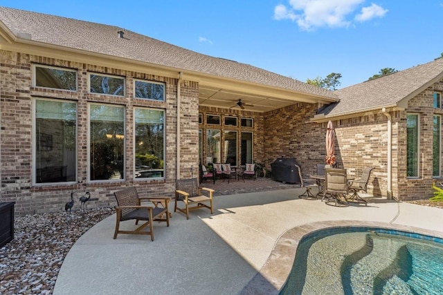 back of house featuring a ceiling fan, an outdoor pool, a patio area, and brick siding