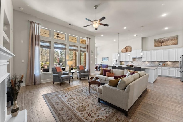 living room with recessed lighting, a fireplace, a ceiling fan, visible vents, and light wood-type flooring