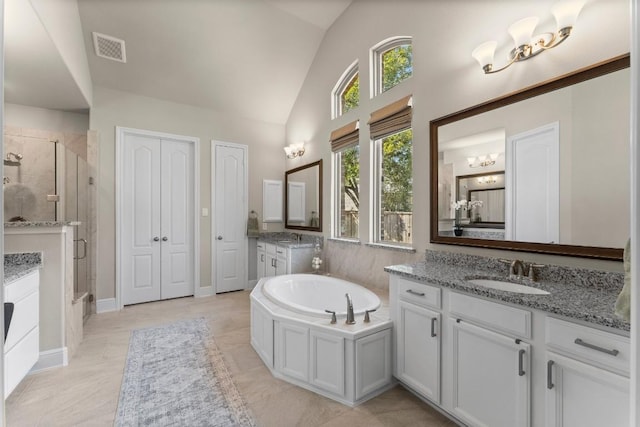 bathroom featuring visible vents, a sink, vaulted ceiling, a shower stall, and two vanities