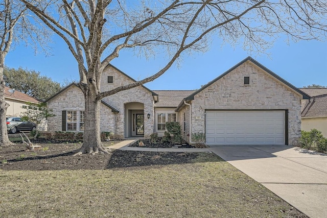 french country home with stone siding, concrete driveway, and an attached garage