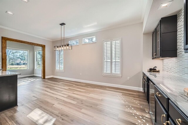 102 Blue Sky Ct, Georgetown, TX 78633 - kitchen featuring dark cabinetry, tasteful backsplash, light wood-style flooring, crown molding, and light stone counters