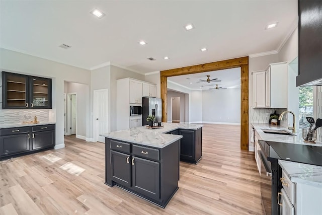 102 Blue Sky Ct, Georgetown, TX 78633 - kitchen with a kitchen island, stainless steel fridge, crown molding, white cabinets, and tasteful backsplash