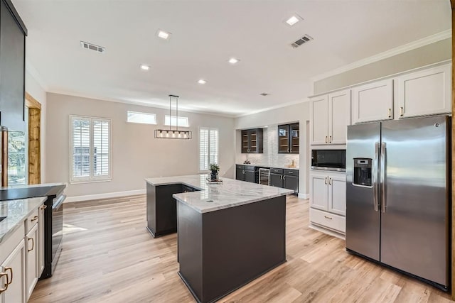 102 Blue Sky Ct, Georgetown, TX 78633 - kitchen featuring stainless steel appliances, ornamental molding, an island with sink, light wood-style floors, and healthy amount of natural light