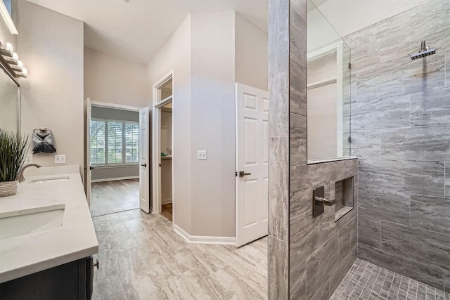 full bath with walk in shower, a sink, double vanity, and baseboards
