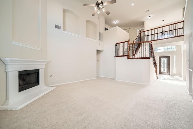1003 Preserve Pl, Round Rock, TX 78665 - unfurnished living room with a towering ceiling, a ceiling fan, carpet, stairway, and a fireplace with raised hearth