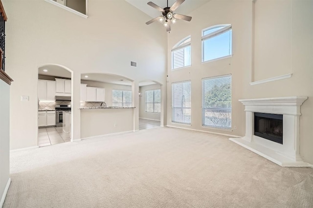 1003 Preserve Pl, Round Rock, TX 78665 - unfurnished living room featuring a high ceiling, light colored carpet, ceiling fan, arched walkways, and plenty of natural light
