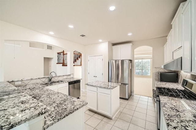 1003 Preserve Pl, Round Rock, TX 78665 - kitchen featuring stainless steel appliances, arched walkways, a sink, a kitchen island, and white cabinets