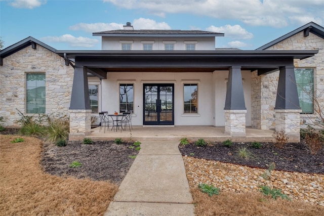 view of exterior entry with stucco siding and covered porch