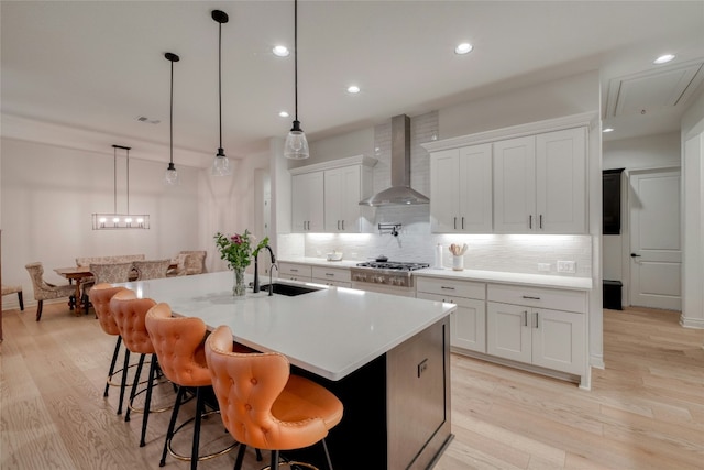 521 Wonderstruck, Liberty Hill, TX 78642 - kitchen with wall chimney exhaust hood, backsplash, light wood-style flooring, white cabinetry, and light countertops