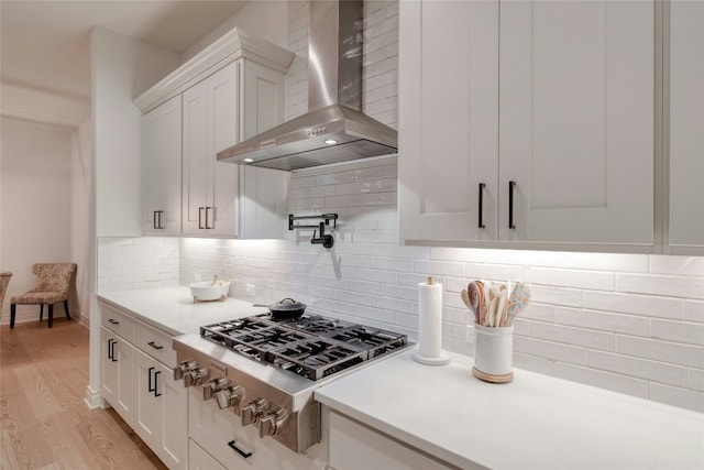 521 Wonderstruck, Liberty Hill, TX 78642 - kitchen with wall chimney exhaust hood, stainless steel gas cooktop, white cabinets, light countertops, and light wood finished floors