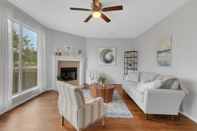 living room with a fireplace, wood finished floors, a ceiling fan, visible vents, and baseboards