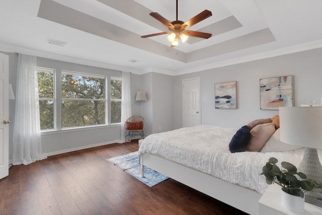 bedroom featuring ornamental molding, a raised ceiling, visible vents, and dark wood finished floors