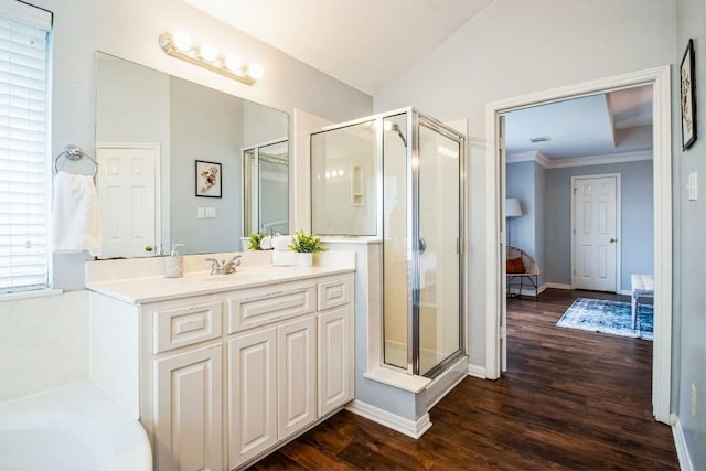 ensuite bathroom featuring a stall shower, vaulted ceiling, vanity, wood finished floors, and baseboards