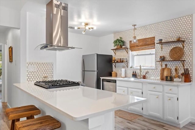 kitchen with a sink, white cabinetry, light countertops, appliances with stainless steel finishes, and island exhaust hood